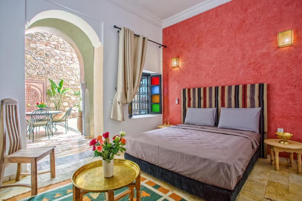 une chambre avec un lit et un mur rouge dans l'établissement Riad Leila Marrakech, à Marrakech