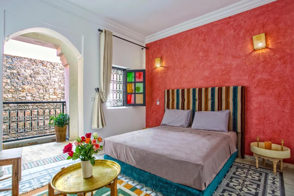une chambre avec un lit et un mur rouge dans l'établissement Riad Leila Marrakech, à Marrakech