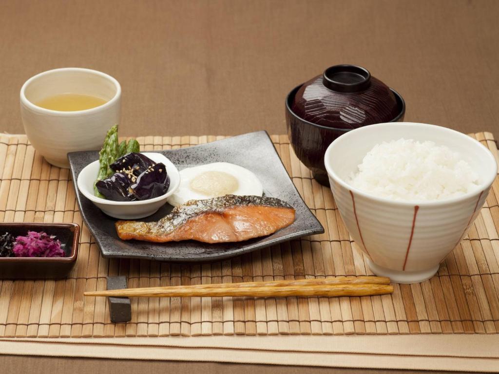 - une table avec une assiette de nourriture et un bol de riz dans l'établissement ホテルファインシエル出雲空港店 - 大人専用, à Izumo