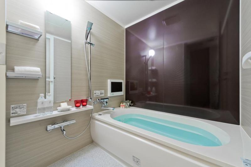 La salle de bains est pourvue d'une baignoire, d'un lavabo et d'une télévision. dans l'établissement Hotel ROY YOKOHAMA, à Yokohama