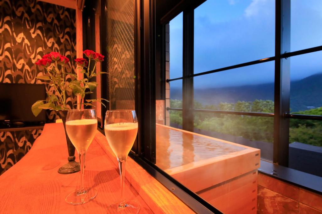 deux verres de vin blanc assis sur une table avec des fleurs dans l'établissement Bettei Koyoi - Adult Only, à Hakone