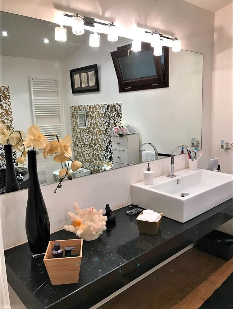 une salle de bain avec un lavabo et un grand miroir dans l'établissement The queen's house, à Agrigente