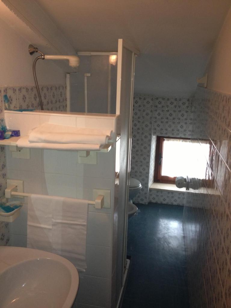 une salle de bain avec un lavabo et des toilettes et une fenêtre dans l'établissement Hotel Rivamare, à Massignano
