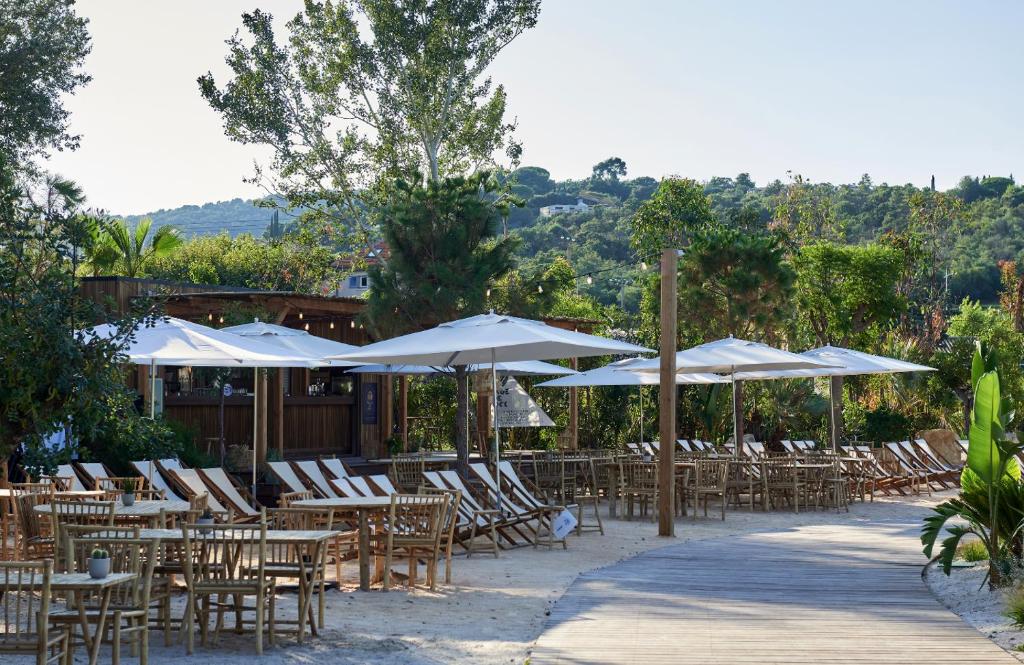 un groupe de tables et de chaises avec parasols dans l'établissement Nova Lodges, à Grimaud 32 autres photos