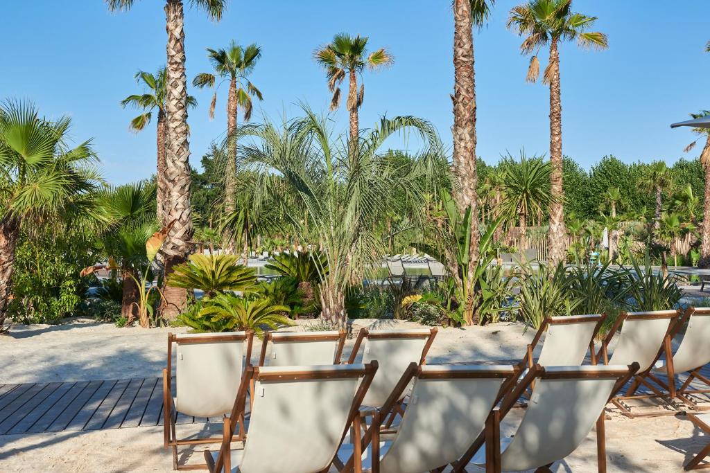 - un groupe de chaises sur la plage avec des palmiers dans l'établissement Nova Lodges, à Grimaud