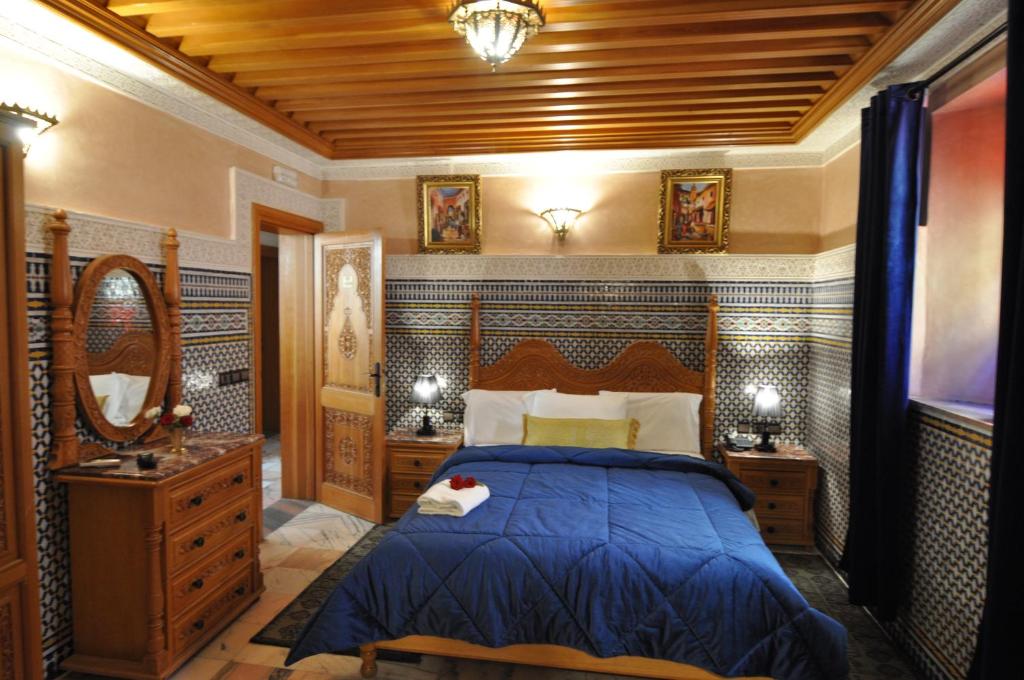 une chambre avec un lit bleu et un miroir dans l'établissement Dar Al Madina Al Kadima, à Fès