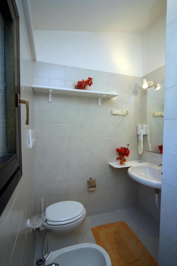 une salle de bain blanche avec toilettes et lavabo dans l'établissement Residence Baia Salinedda, à San Teodoro