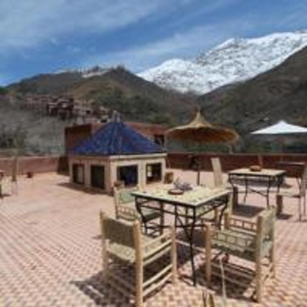 un patio avec une table et des chaises et une montagne dans l'établissement Imlil Lodge, à Imlil