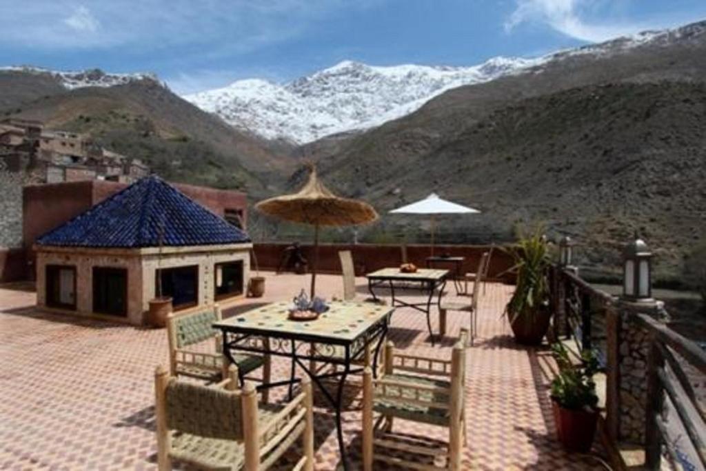 d'une terrasse avec des tables et des chaises et des montagnes en arrière-plan. dans l'établissement Imlil Lodge, à Imlil