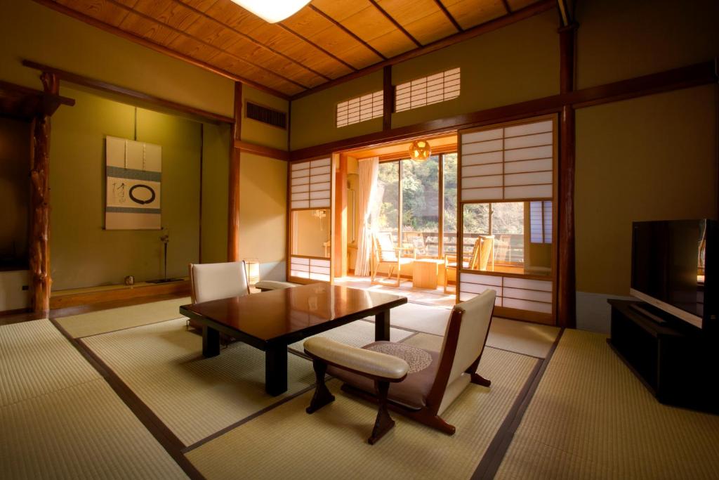 un salon avec une table, des chaises et une télévision dans l'établissement Seiryu-so, à Shimoda