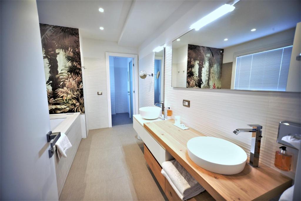 une salle de bain avec deux lavabos et un grand miroir dans l'établissement Grande Albergo Marin, à Lignano Sabbiadoro