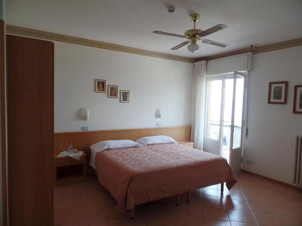 une chambre avec un lit et un ventilateur de plafond dans l'établissement Piccolo Hotel Direkt am See, à Brenzone