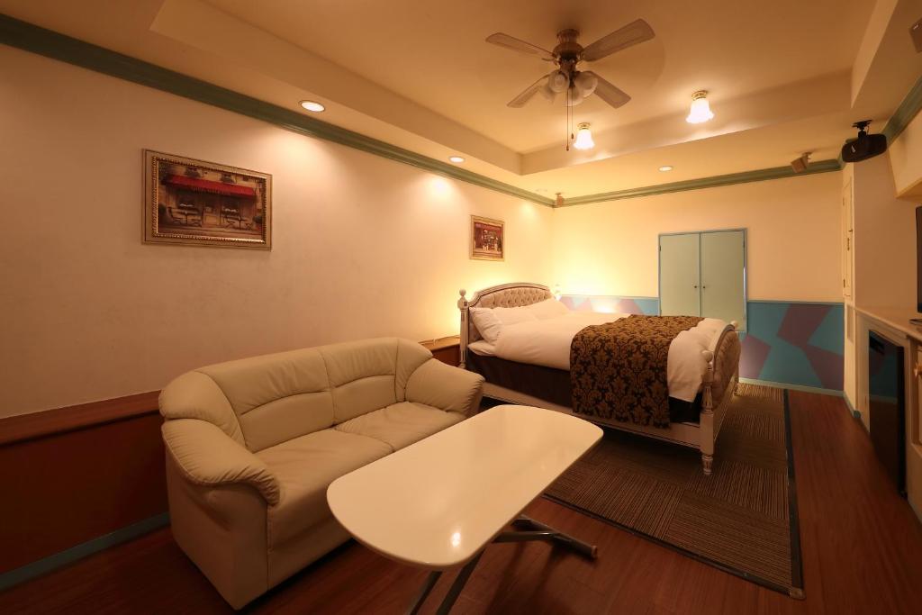 une chambre avec un lit, un canapé et une chaise dans l'établissement ホテルファインシエル島根松江店 - 大人専用, à Matsue