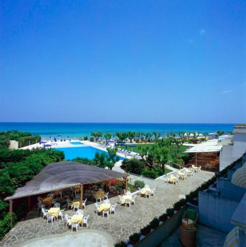 un groupe de tables et de chaises à côté d'une piscine dans l'établissement Hotel Del Levante, à Torre Canne