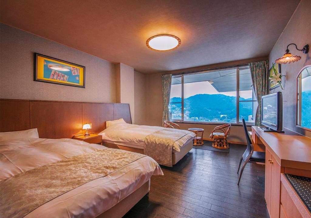 une chambre d'hôtel avec deux lits, un bureau et une fenêtre dans l'établissement Ryoso Uminocho, à Ise