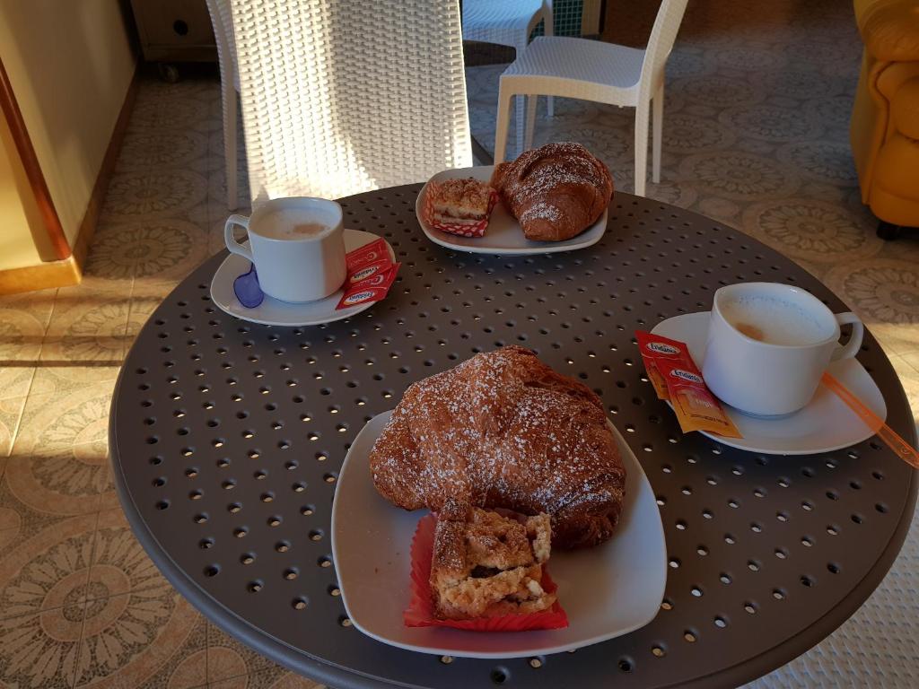 deux tasses de café et deux assiettes de pâtisseries sur une table dans l'établissement Hotel Rosy, à Battipaglia