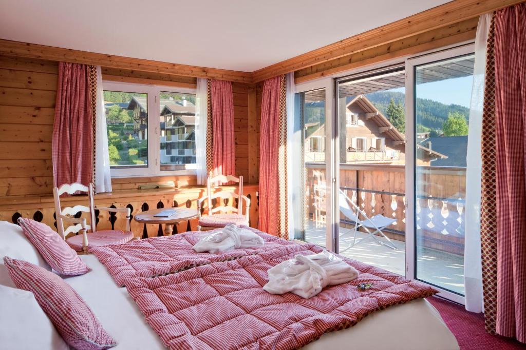 une chambre avec un grand lit et un balcon dans l'établissement Chalet-Hôtel La Marmotte, La Tapiaz & SPA, The Originals Relais, aux Gets