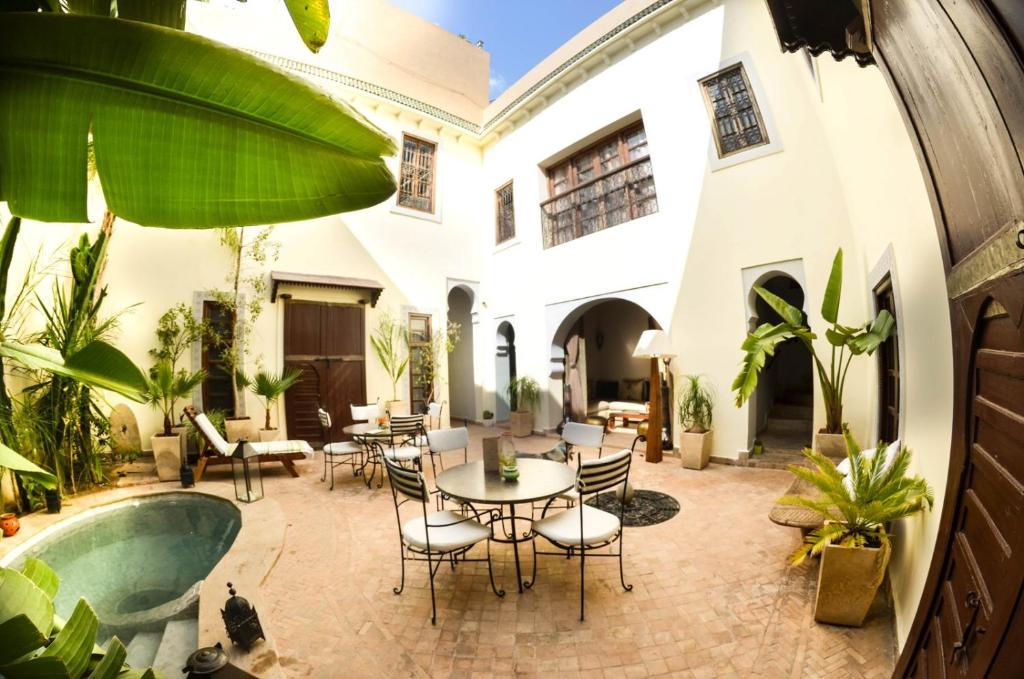 un patio extérieur avec une table et des chaises ainsi qu'une piscine dans l'établissement Riad les Ammonites and Spa, à Marrakech