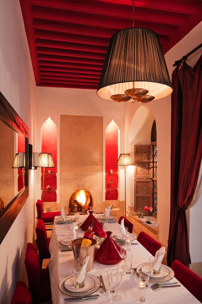 une salle à manger avec une grande table et une cheminée dans l'établissement Riad Tzarra, à Marrakech