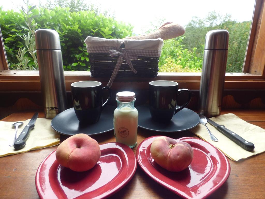 deux pommes sur des assiettes rouges sur une table avec deux tasses dans l'établissement D'tente sky lodge, à Massat