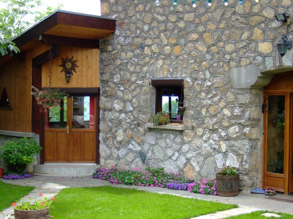 une maison en pierre avec une porte en bois et des fleurs dans l'établissement Domaine du Rocher St-Loup, à Vif