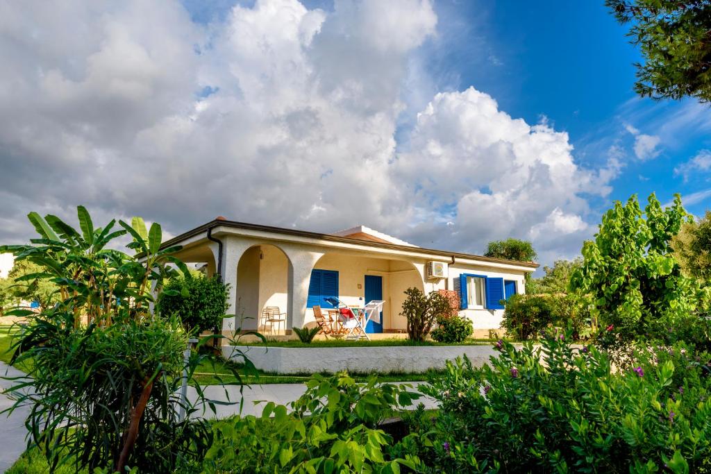 une maison blanche avec des volets bleus et des arbres dans l'établissement TUISuneo La Conchiglia - Adults Only, à Capo Vaticano