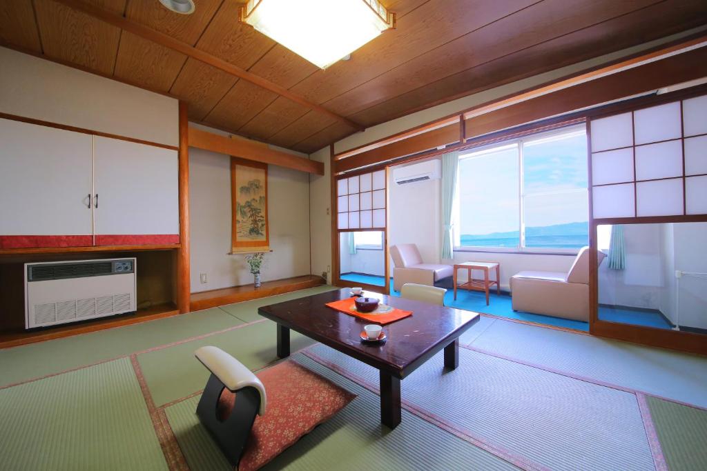 - un salon avec une table, des chaises et une télévision dans l'établissement Lake Side Hotel Minatoya, à Inawashiro