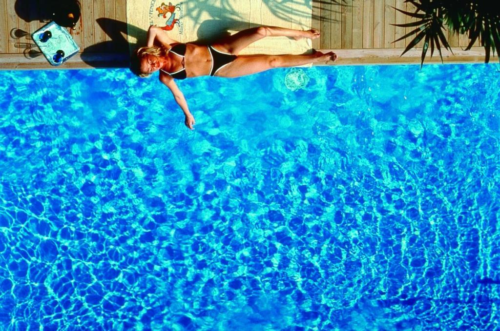une femme en bikini flottant dans une piscine dans l'établissement Hotel Fenice Gluten Free, à Milano Marittima