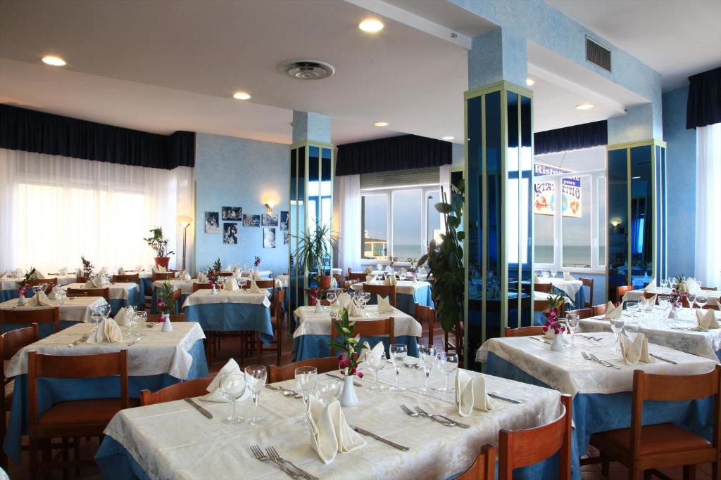 une salle à manger avec des tables et des chaises avec des nappes blanches dans l'établissement Hotel Giannino, à Porto Recanati