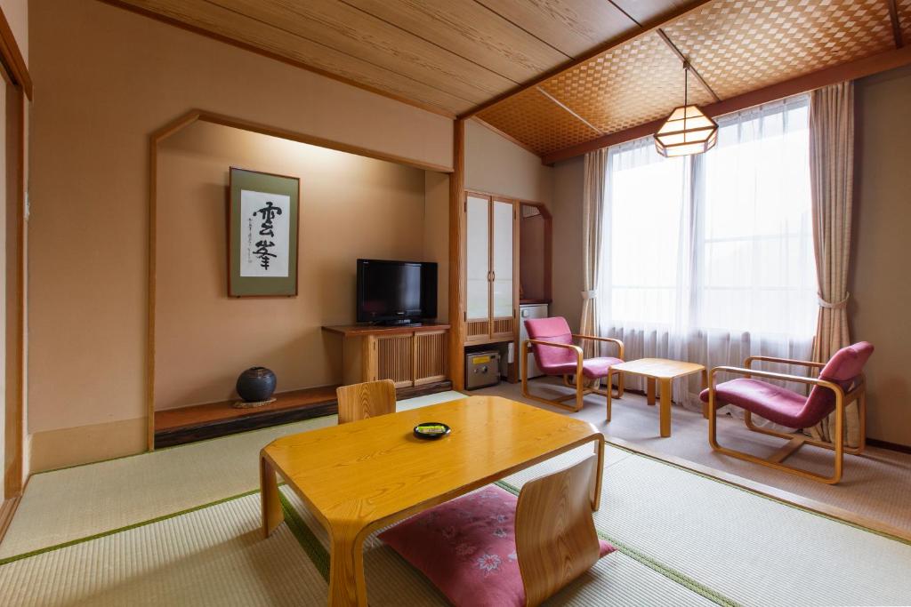 un salon avec une table, des chaises et une télévision dans l'établissement Choyo Tei, à Kamikawa