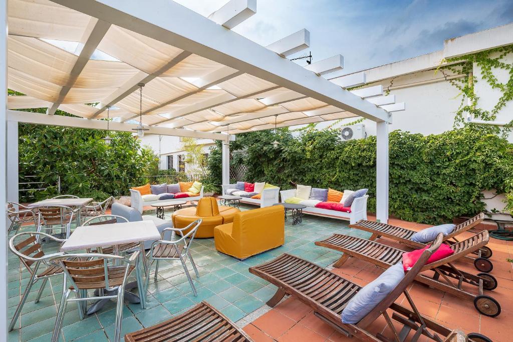 un patio extérieur avec chaises et tables et une pergola dans l'établissement Hotel Santa Maria, à Santa Maria Navarrese