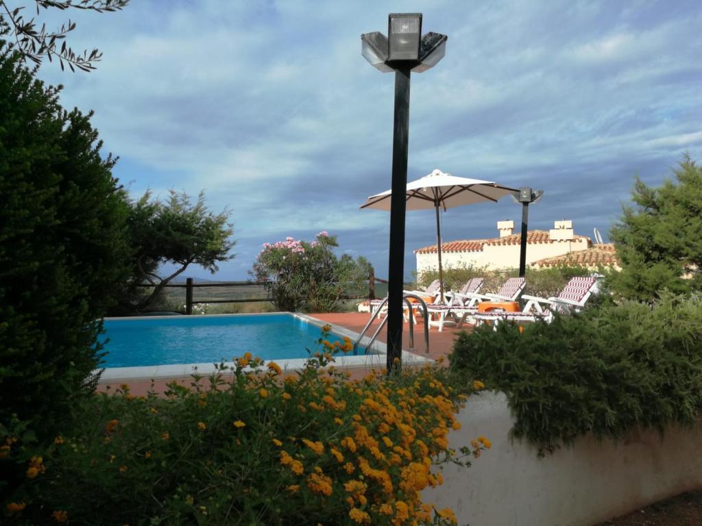 - une piscine avec un parasol et des chaises dans l'établissement Villa con Piscina Stintino, à Stintino