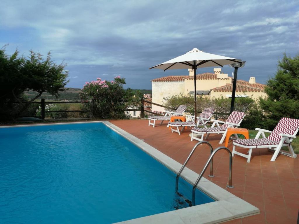 une piscine avec des chaises et un parasol dans l'établissement Villa con Piscina Stintino, à Stintino
