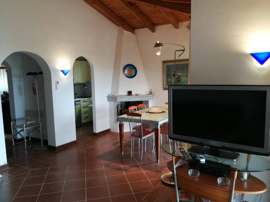 un salon avec une télévision et une table avec des chaises dans l'établissement Villa con Piscina Stintino, à Stintino
