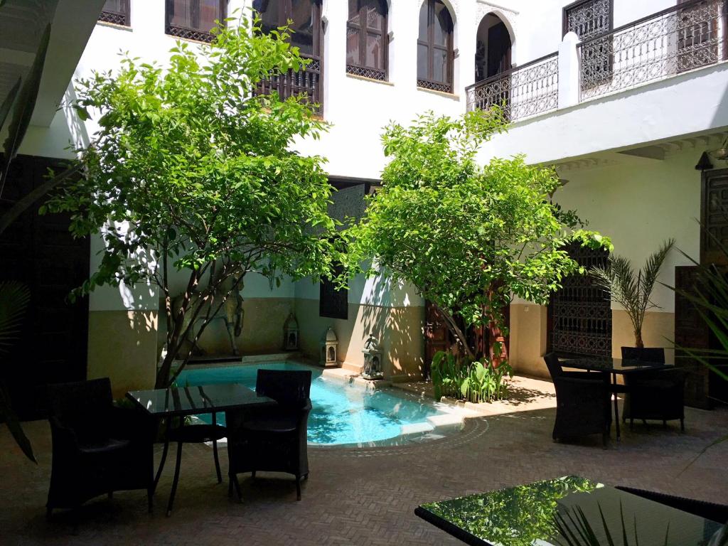une cour avec une table, des chaises et des arbres dans l'établissement Riad Assakina, à Marrakech