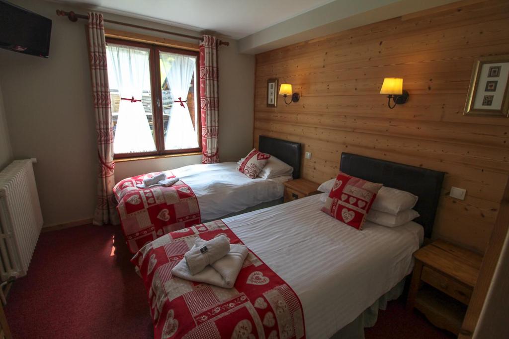- une chambre avec 2 lits et des couvertures rouges et blanches dans l'établissement Hotel Le Christiania, aux Gets