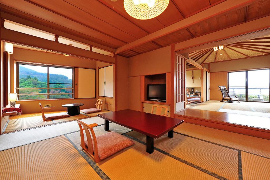 un salon avec une table et une grande fenêtre dans l'établissement Oyado Tamaki, à Shibukawa