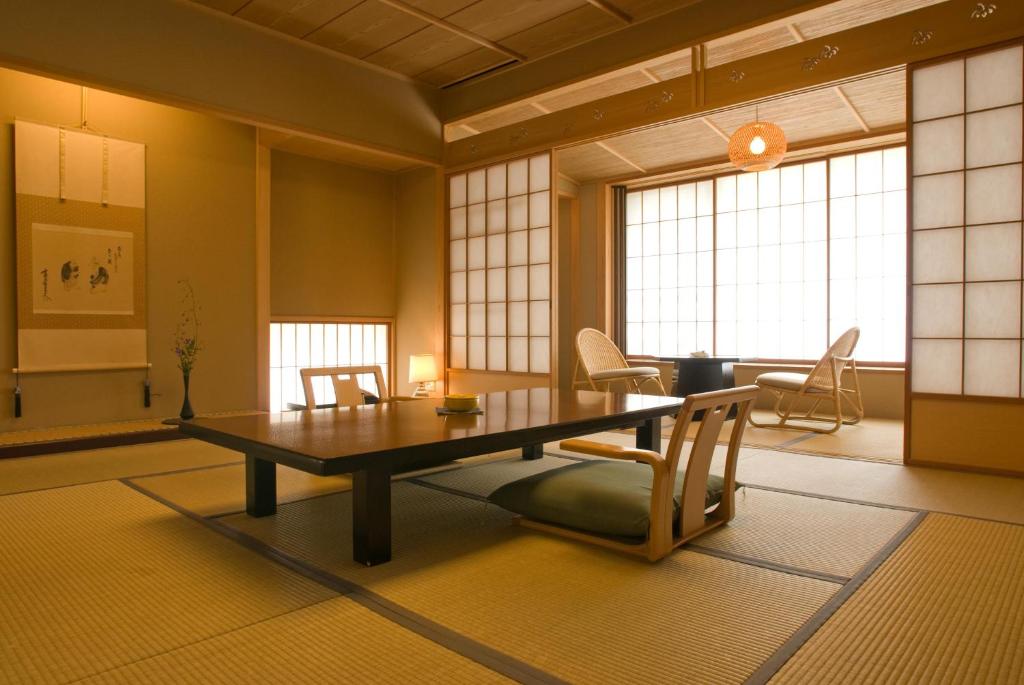 un salon avec une table, des chaises et des fenêtres dans l'établissement Oyado Tamaki, à Shibukawa