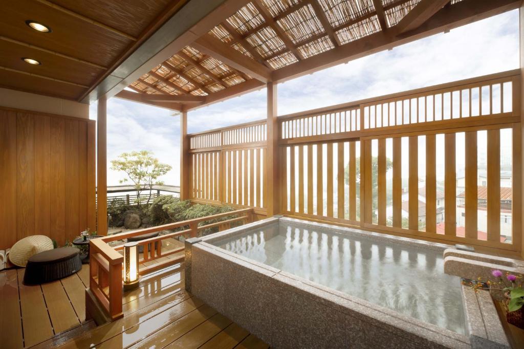 - une grande piscine dans une chambre avec une terrasse en bois dans l'établissement Oyado Tamaki, à Shibukawa