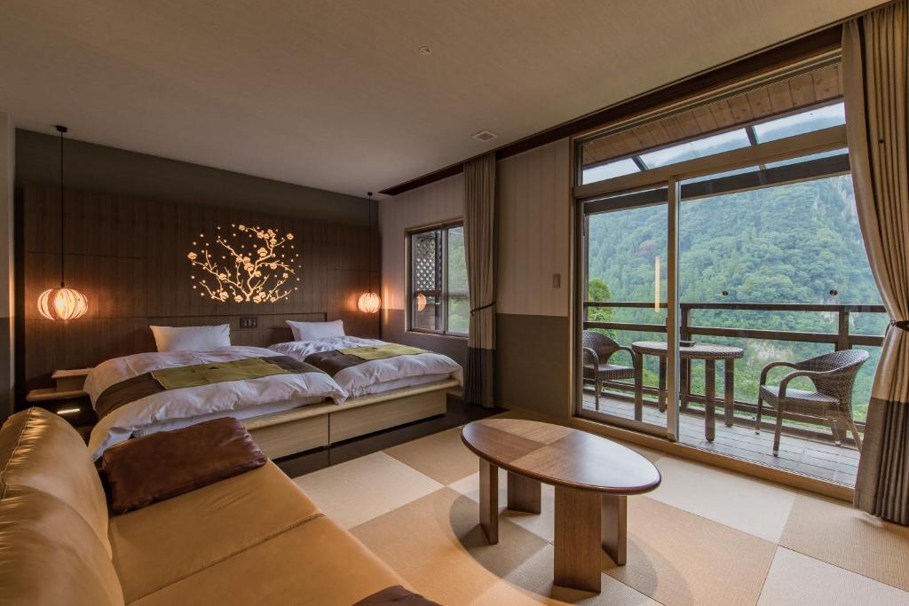 une chambre avec un lit, un canapé et une fenêtre dans l'établissement Okuhita Onsen Umehibiki, à Hita