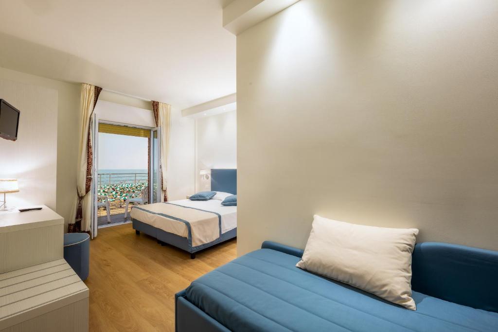 une chambre avec un canapé bleu et un lit dans l'établissement Hotel Ariston, à Caorle