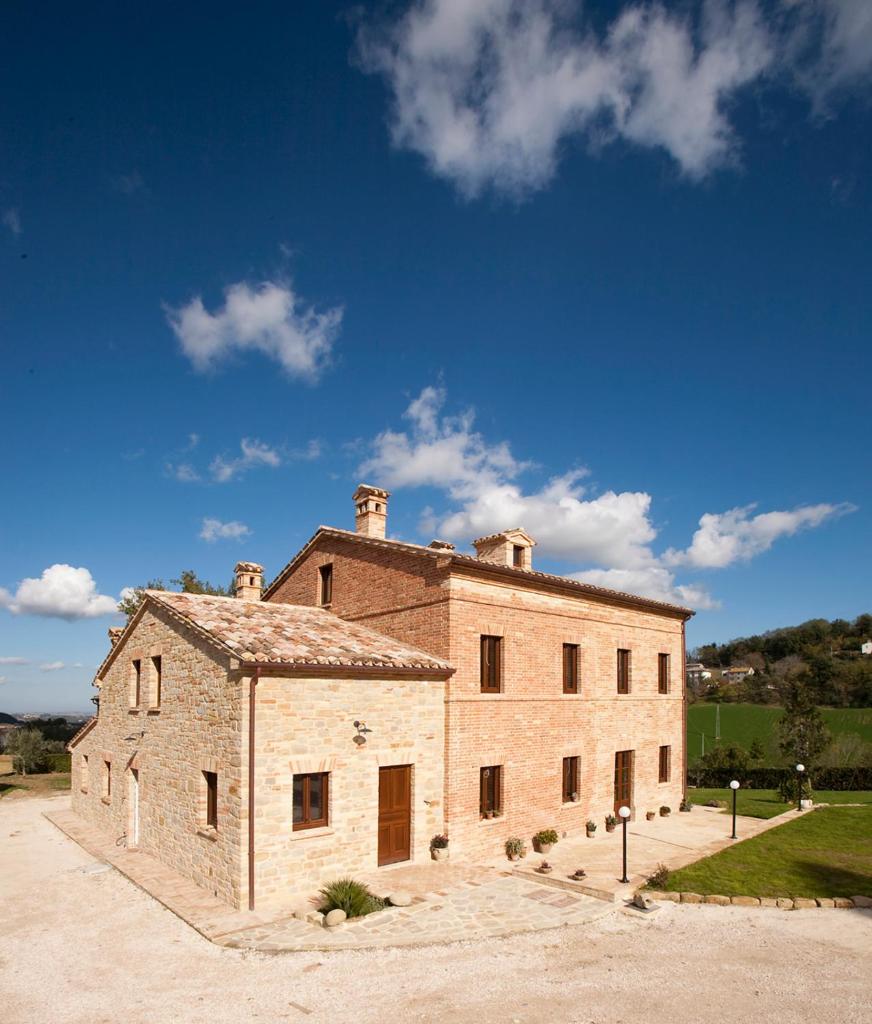 un grand bâtiment en briques avec un ciel bleu en arrière-plan dans l'établissement Collerovere Country House, à SantʼAngelo in Pontano