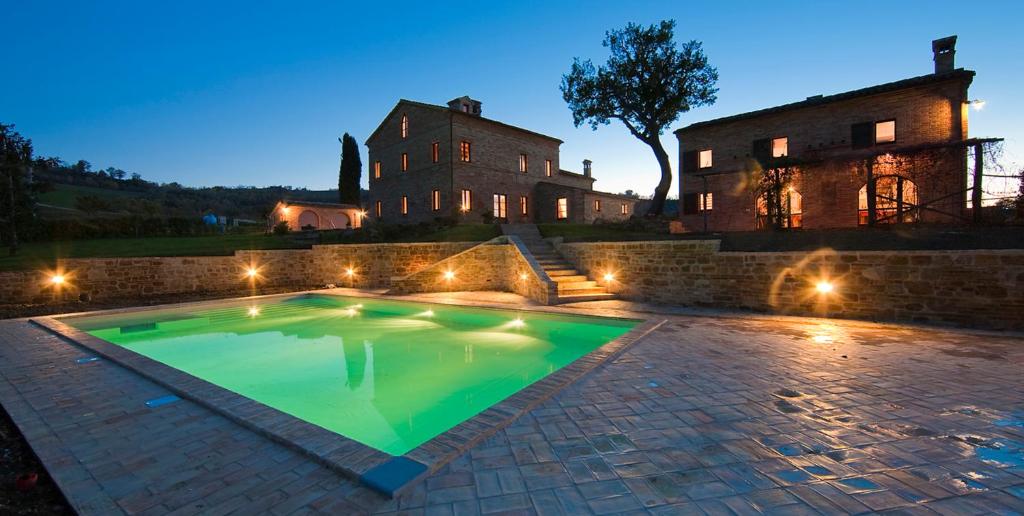 une piscine devant une maison la nuit dans l'établissement Collerovere Country House, à SantʼAngelo in Pontano