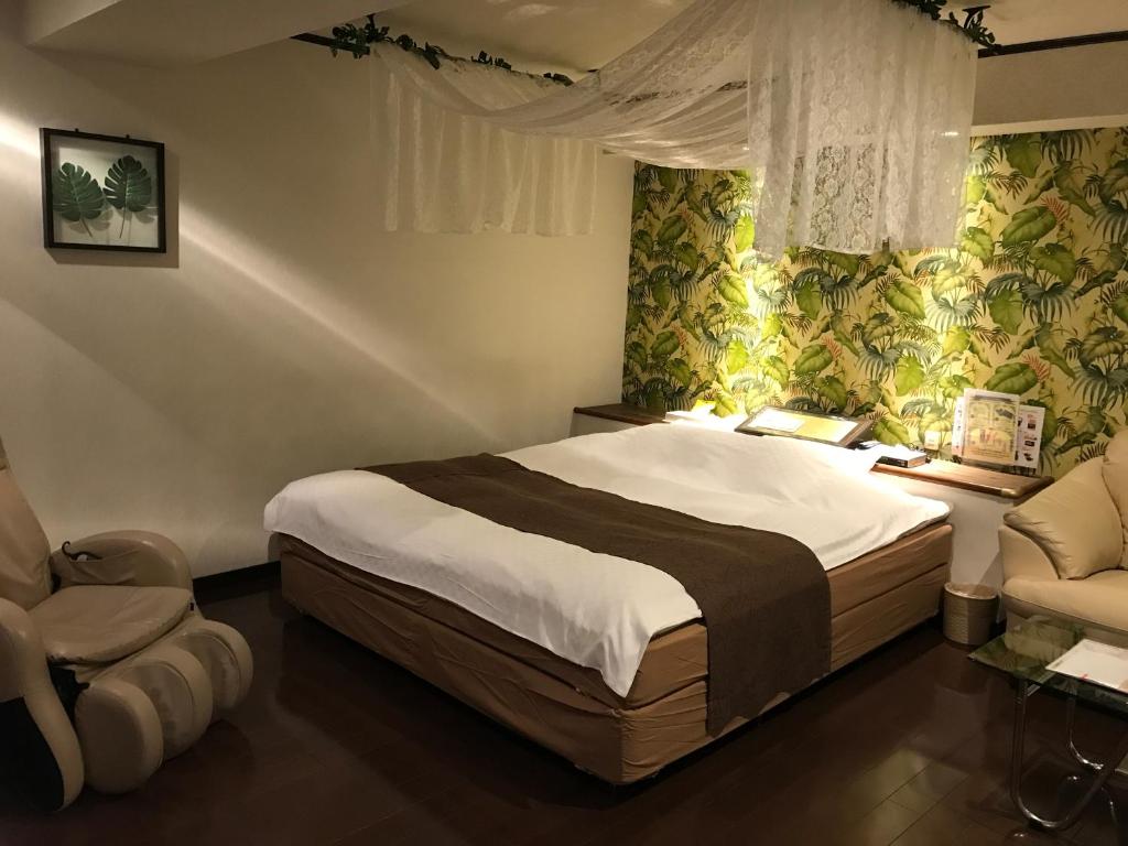 une chambre avec un grand lit et une chaise dans l'établissement Ciao-LoveHotel, à Miyazaki