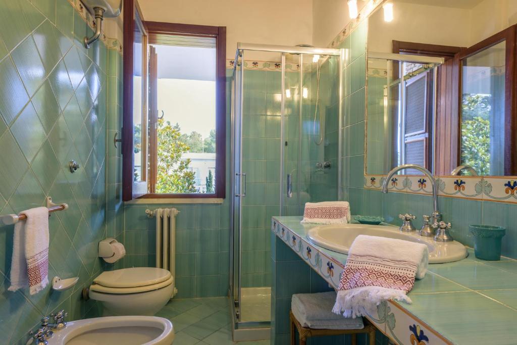 une salle de bain avec un lavabo, des toilettes et une douche dans l'établissement Villa Il Melograno, à San Cataldo