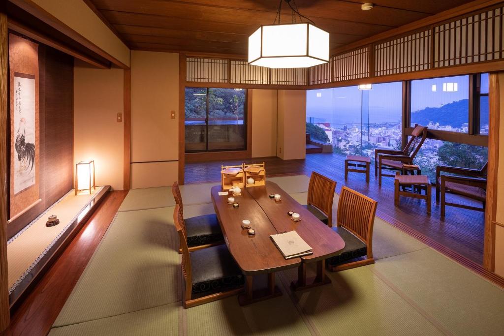 une salle à manger avec une table, des chaises et des fenêtres dans l'établissement Watei Kazekomichi, à Atami
