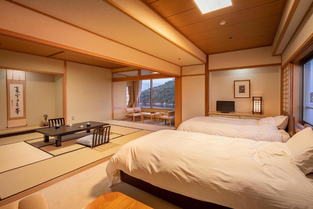- une chambre avec 2 lits, une table et une télévision dans l'établissement Sansuikan Kinryu, à Hamamatsu