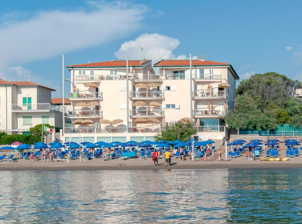une plage avec des chaises et des parasols et un bâtiment dans l'établissement Residence Villa Lo Scoglietto, à San Vincenzo