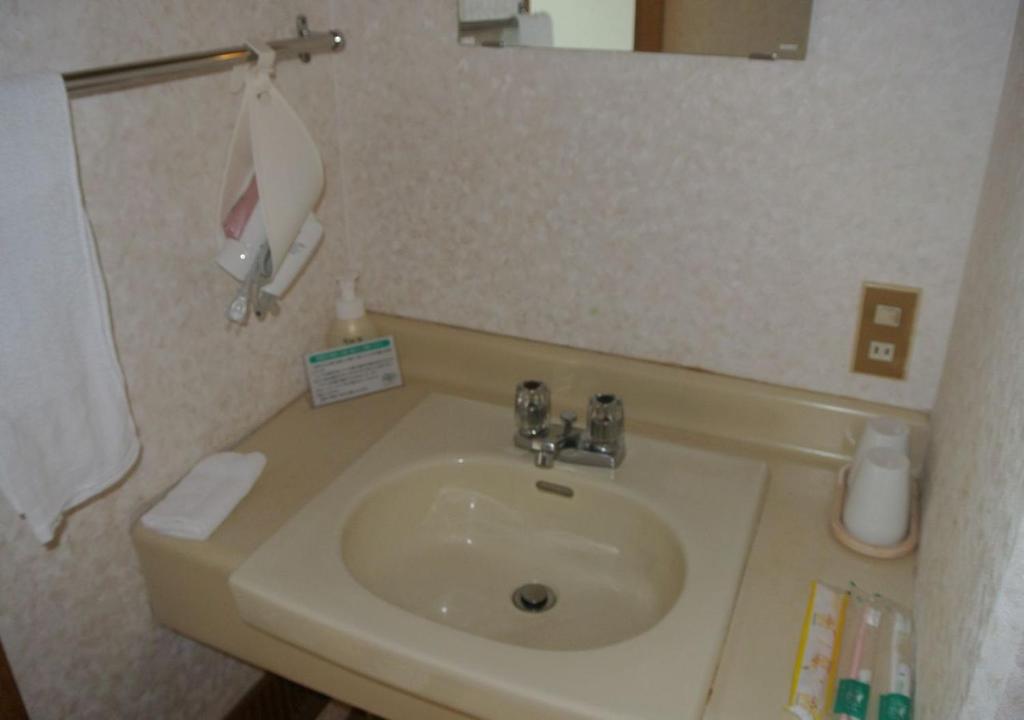 une salle de bain avec un lavabo blanc et un miroir dans l'établissement Kyukamura Ohkunoshima, à Takekara