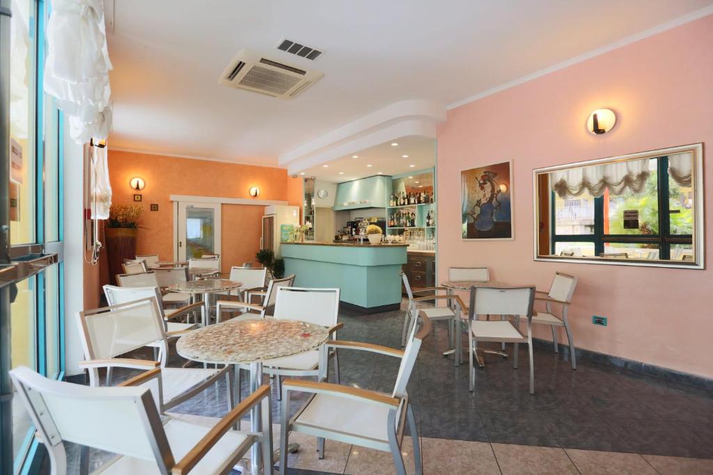 un restaurant avec des tables, des chaises et un comptoir dans l'établissement ELISABETTA hotel, à Cesenatico